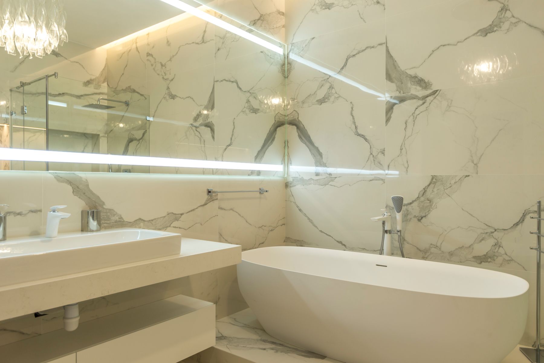 Marble bathroom with a freestanding tub, vanity, and glass shower